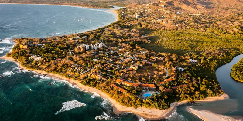 Aerial view at golden hour over Playa Langosta, Tamarindo and its estuary, with Playa Grande beyond
