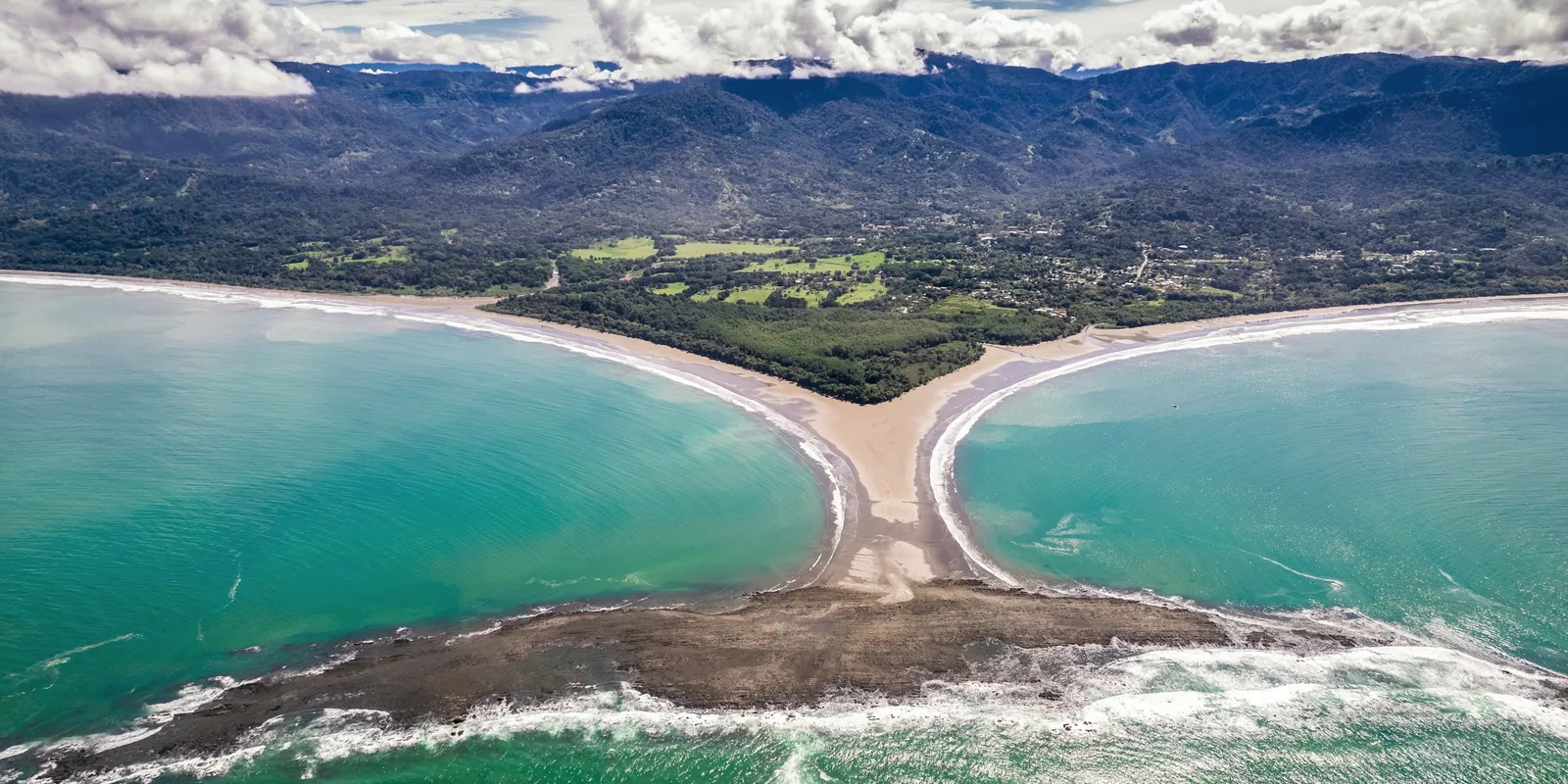The whale-tail sandbar of Bahía Ballena from the sea, with the coastal mountains behind