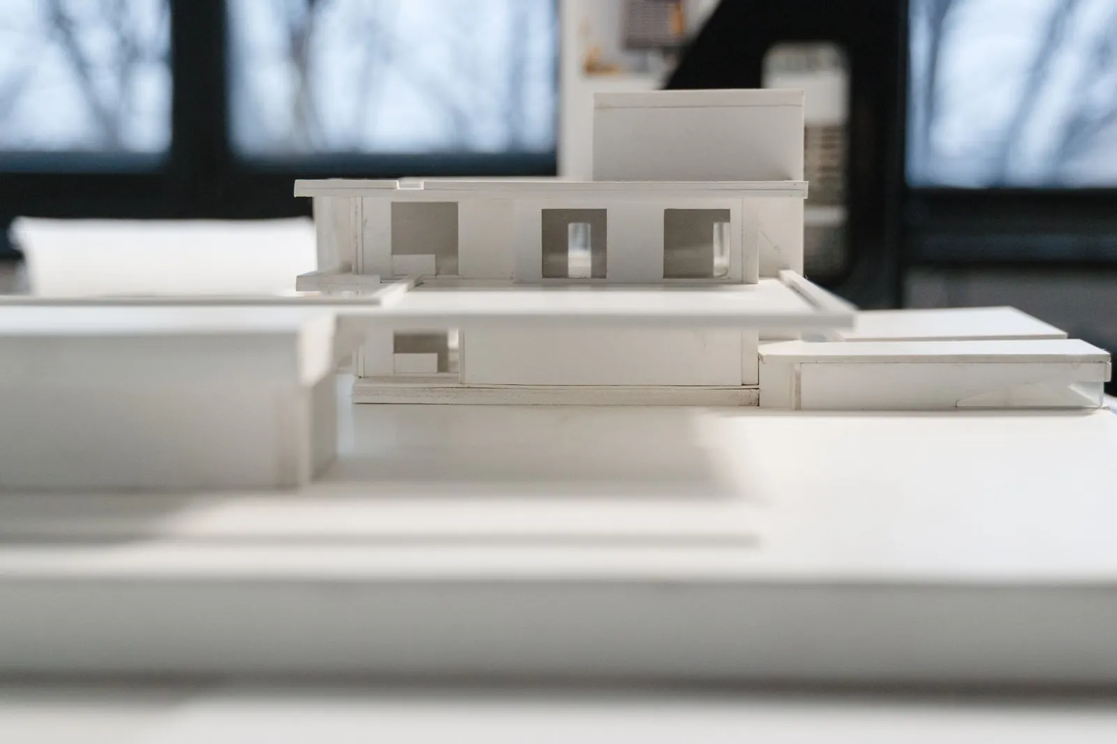 A white card house model on a desk in soft daylight